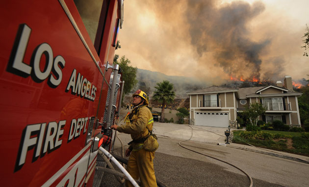 Wildfires California: A firefighter monitors a fire burning behind houses in Glendale 