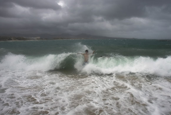 24 hours: Cabo San Lucas, Mexico: A man swims amidst crashing waves
