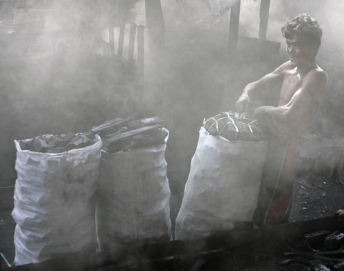 21 September 2009: Manila, Philippines: A man packs sacks of charcoal at a garbage dump
