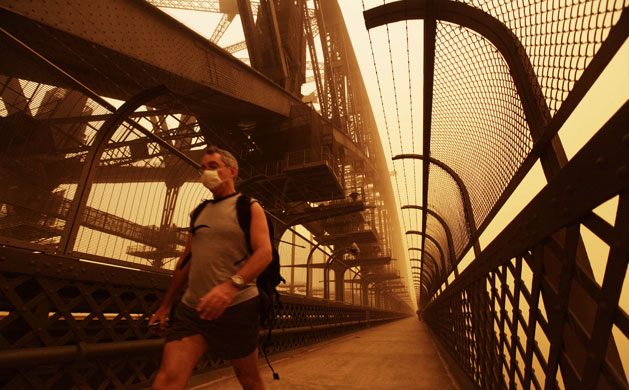 Sydney dust storm: A man wearing a dust mask walks across the Sydney Harbour bridge