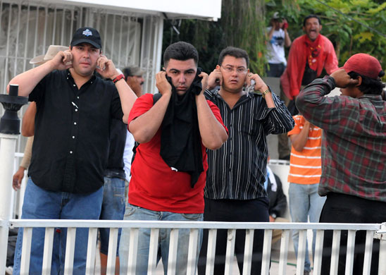 Honduras crisis : Zelaya supporters cover their ears as police use sound to disperse them