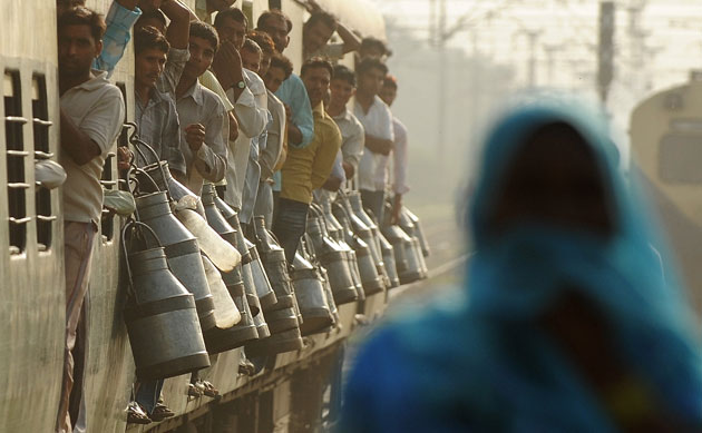 24 hours in pictures: Milk cans hang from a passing train in New Delhi