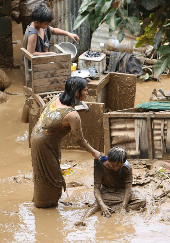 Philippines floods: Filipinos are drenched in mud as they recover belongings from damaged homes