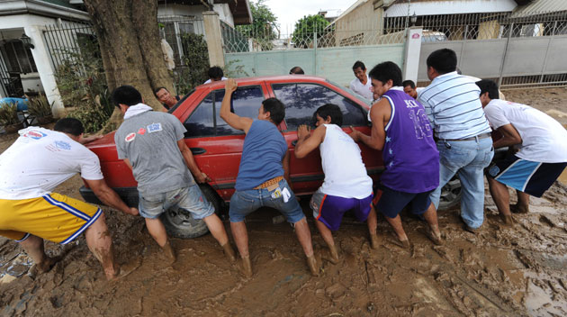 Philippines floods: A group of men attempt to move a car as flood waters recede