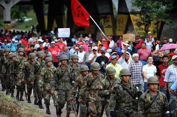 Honduras crisis: Honduran soldiers march next to supporters of the ousted president Zelaya 