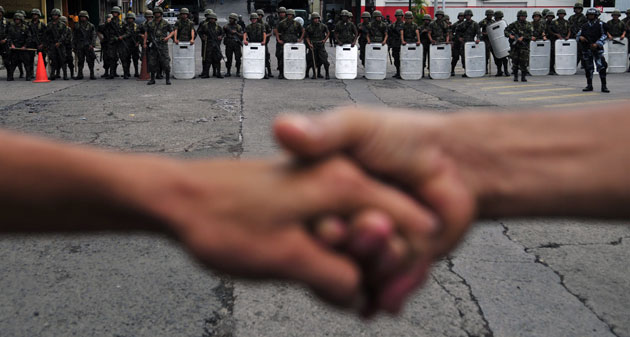 Honduras crisis: Supporters of Zelaya form a human chain as soldiers watch over them