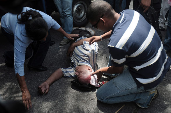 Honduras crisis: A supporter of President Micheletti is assisted after been hit by a rock