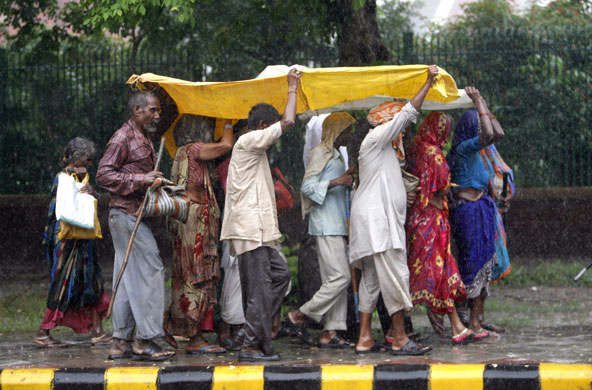 3 September 2009: New Delhi, India: Pedestrians shelter themselves from rain