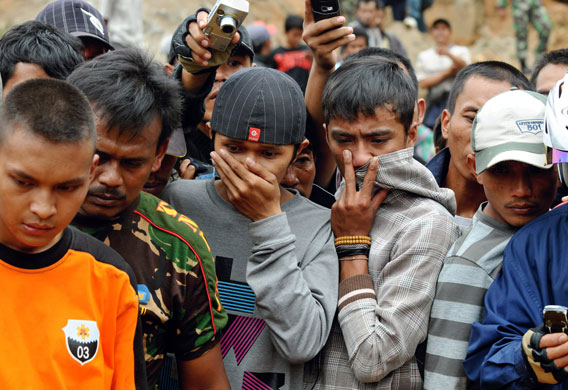 3 September 2009: Java: Residents watch as soldiers, police and villagers lift a dead body