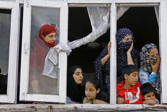 7 September 2009: Srinagar, India: Kashmiris peep out from the window of their house