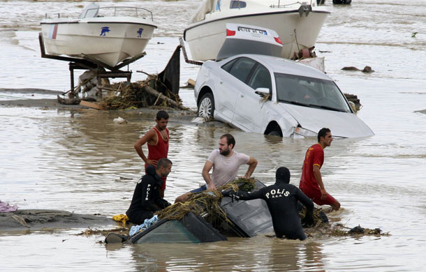 Flooding in Turkey: Police and local men surround a partially submerged vehicle