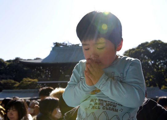 24 hours: A young boy prays during a visit to Meiji shrine in Tokyo