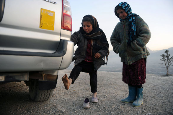 24 hours in pictures: Kabul, Afghanistan: Girls warm their feet over the exhaust of a car 