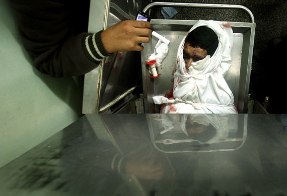 24 hours in pictures: Gaza strip: A man takes a photo of the body of a Hamas militant