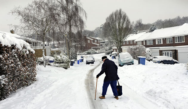Snow again: An elderly man walks home from the local shop in Hartley Wintney