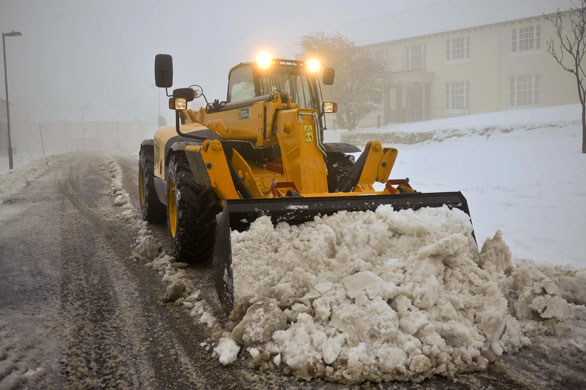 Snow again: A JCB digger clears snow in Princetown, Dartmoor, Devon