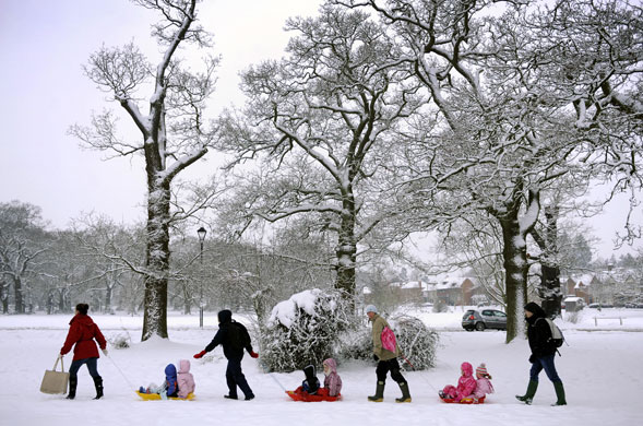 Snow again: Mothers tow children on their sledges across the village green