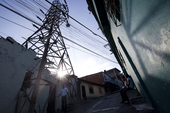 24 hours: People walk along a street in front of an electricity pylon in Caracas