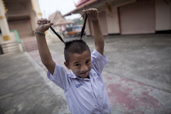 24 hours: Noi Klong, Thailand: A schoolboy shows off his traditional haircut  