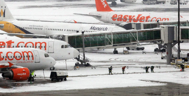 Snowing again: Firemen clear snow from the taxi way at Gatwick Airport