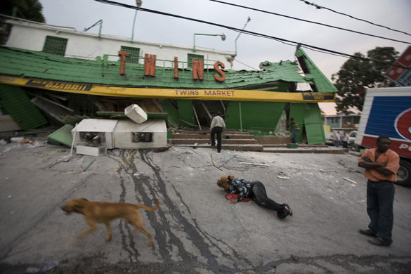 haiti update 3: A woman lies on the ground as others stand outside market Haiti earthquake