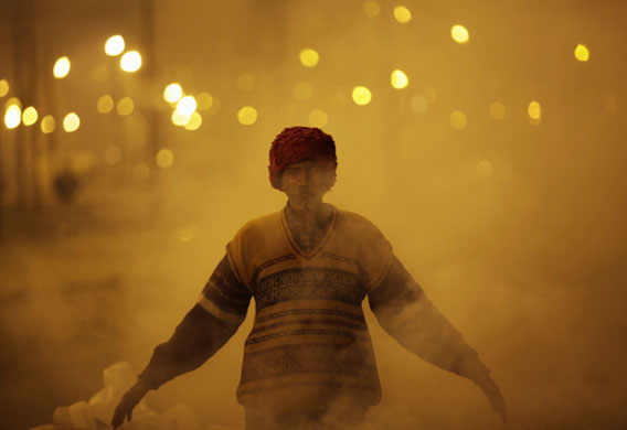 24 hours in pictures: Allahabad, India: A labourer stands in the smoke from a fire