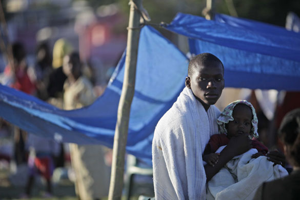 haiti earthquake: A man holds a child in a makeshift camp for earthquake survivors in Haiti 