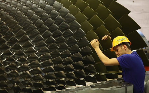 Week in Business: A worker rotates a gas turbine during assembly at the Siemens factory