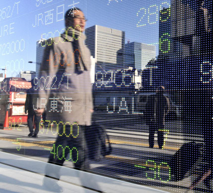 Week in Business: A businessman passes by a share prices board in Tokyo