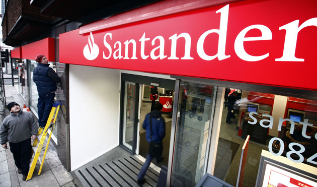 Week in Business: Workers unveil the new Santander branding on a branch