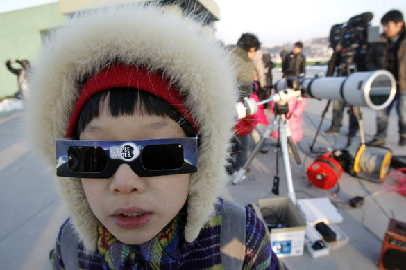 solar eclipse: A South Korean boy watches a solar eclipse through special sunglasses