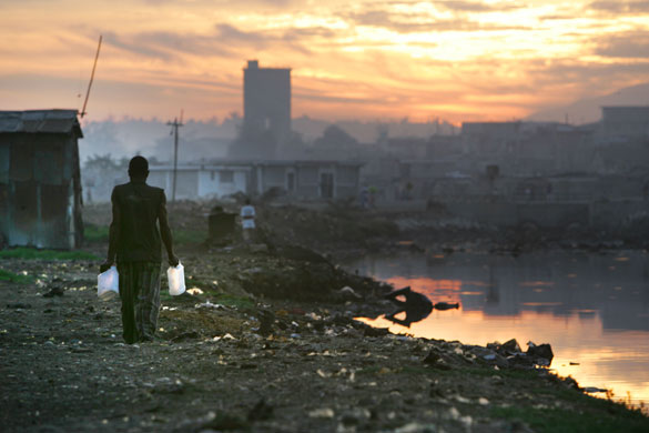 History of Haiti: 2006: At sunrise, a Haitian man walks with empty jugs to fill with water