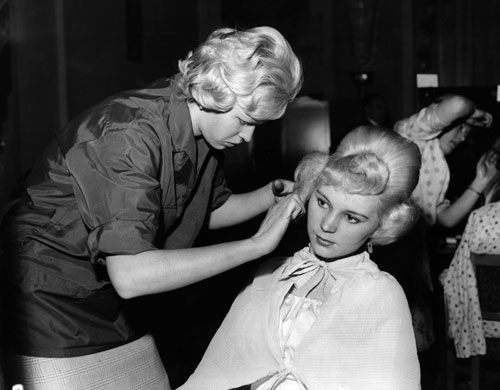 Teenage Hair: A hairdresser finishes a beehive hairstyle on a teenage girl