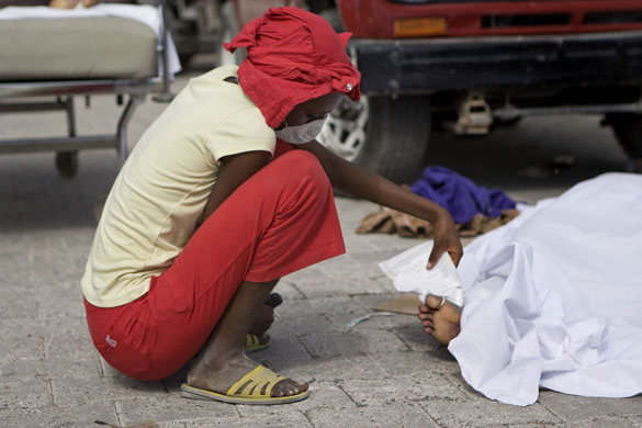 Rescue efforts in Haiti: A woman checks the toe tag on a body in the parking lot