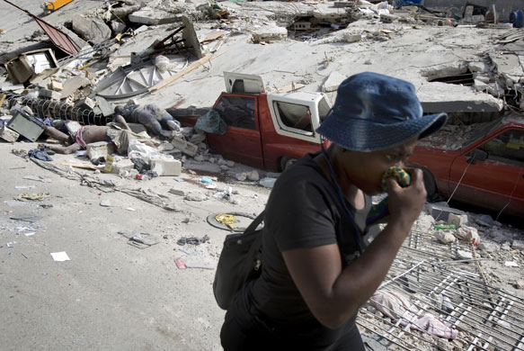 Rescue efforts in Haiti: A woman walks past bodies pulled out of the rubble  in Port-au-Prince