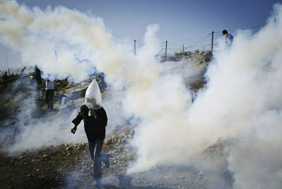24 Hours in Pictures: Palestinians run from tear gas canisters fired by Israeli soldiers