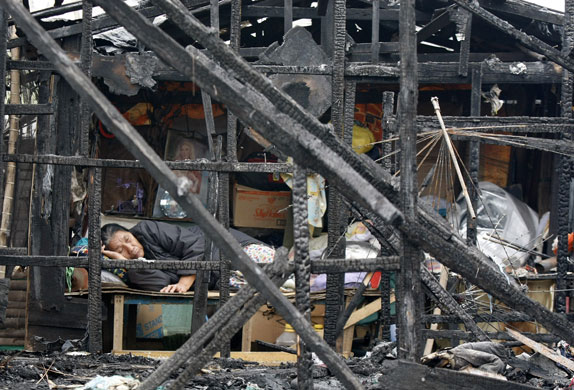 24 hours: Manila, Philippines: A woman sleeps inside her burnt house