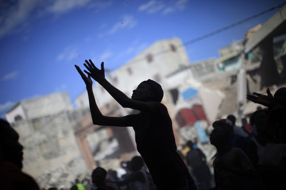 24 hours: Port-au-Prince, Haiti: A woman raises her arms for products as people loot