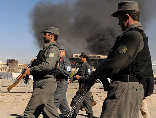 violence in kabul: Afghan policemen walk past a burning building 