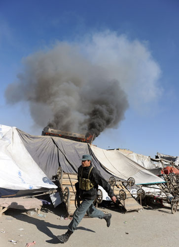 Kabul violence: An Afghan policeman take positions near a burning building
