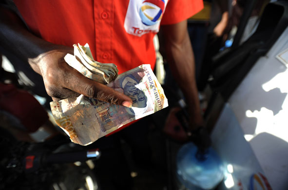 Lawless Haiti: A Haitian fueling station attendant holds a wad of money 