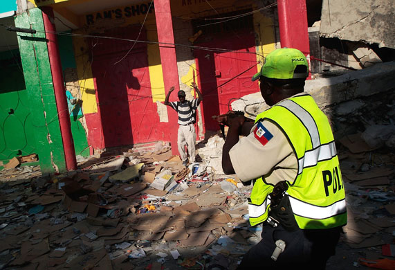 Lawless Haiti: A Haitian police officer points a rifle at a man during a looting spree 