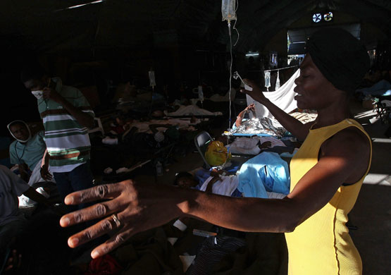 Lawless Haiti: A woman prays over her daughter's bed at a field hospital 