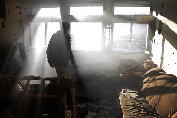 Violence in Kabul: Afghan policeman inspects damage to a building after a gun battle in Kabul