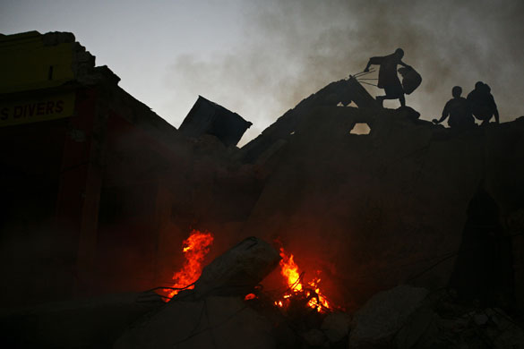 24 hours: Port-au-Prince, Haiti: Scavengers walk over the rubble of buildings 