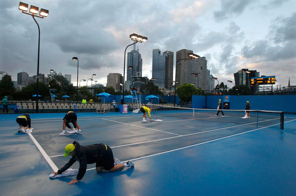tennis: Grounds personnel dry an outer court