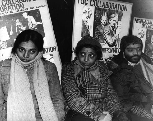 Jayaben Desai: Three strikers sit with placards behind them