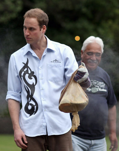 Prince William down under: Prince William lifts food out of the traditional Maori earth oven 