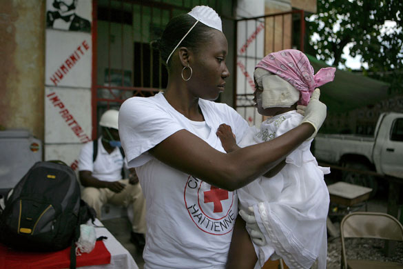 Haiti Aid: Red Cross volunteer Miname Glaude holding Michel Laurent