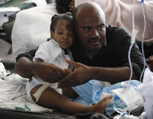 Haiti Aid: A man comforts Desie Ulachine, 7, at a hospital 